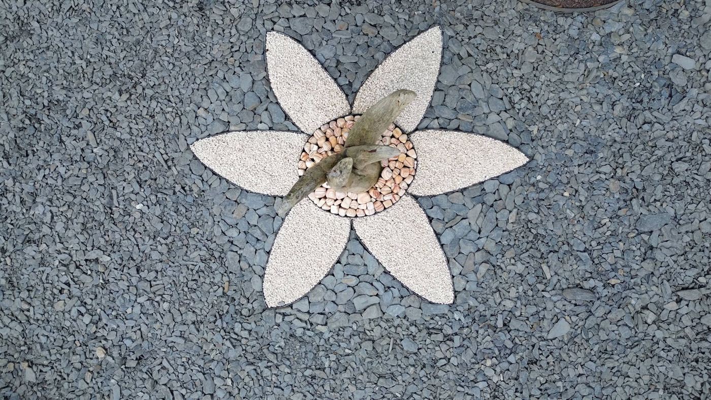 Détail d'une composition minérale en forme de fleur, ardoise et galets